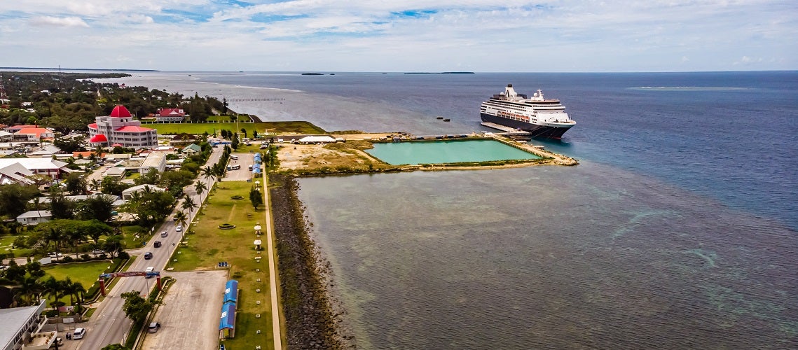 High view of a small pool and a pier with a cruise ship at low tide, Tonga